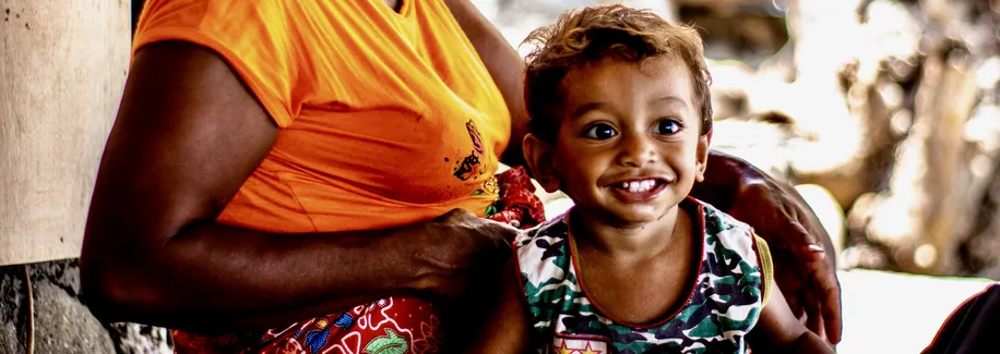Timorese child with woman in bright coloured shirt